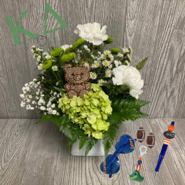 White and green floral arrangement with a teddy bear pick in a square vase