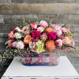 Mixed pink and peach flower arrangement in a rectangular glass vase