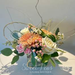 Peach and white rose bouquet with pink blooms in a glass vase