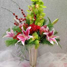 Tall floral arrangement with orchids, roses, and lilies in a gold vase