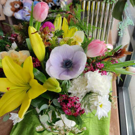 Mixed bouquet with yellow lilies, pink tulips, and a pale purple anemone