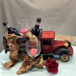 Decorative truck with wine bottles, glass candle holders, and a red rose