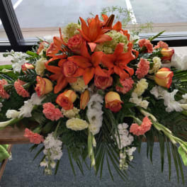 Large floral casket spray with orange lilies and roses