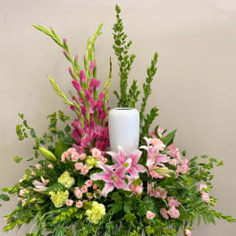 Large floral arrangement with pink lilies, roses, and tall greenery in a white vase