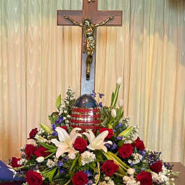 Red roses and white lilies arranged around a crucifix and patriotic egg centerpiece