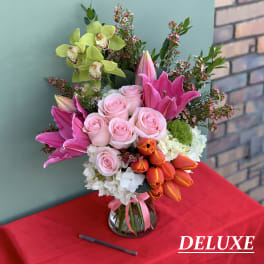 Bouquet of pink roses, lilies, and orchids in a glass vase