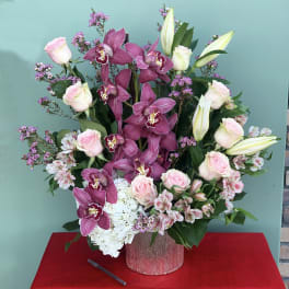 Pink orchids, roses, lilies, and white hydrangea in a glittery vase