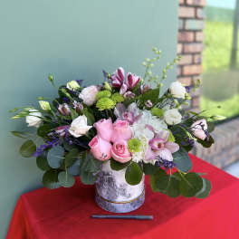 Pink roses and white flowers arranged in a gray vase