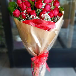 Bouquet of red roses with baby's breath wrapped in tan paper and red ribbon
