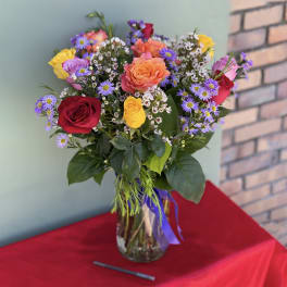 Mixed bouquet of roses and purple daisies in a glass vase