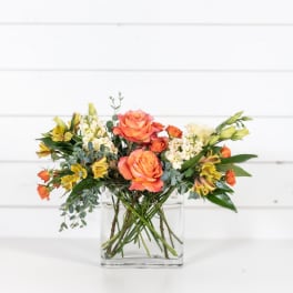 Orange roses and yellow alstroemeria in a clear glass vase