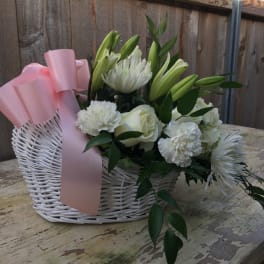 White floral basket with pink ribbon and lilies, roses, and chrysanthemums