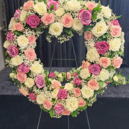 Heart-shaped floral wreath of pink, cream, and lavender roses