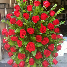 Large standing arrangement of red roses with greenery