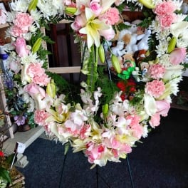 Heart-shaped floral wreath on a stand with pink and white flowers