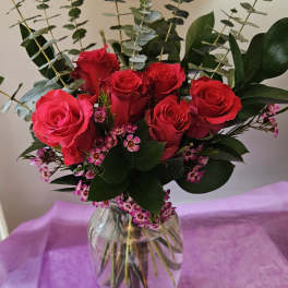 Red roses in a clear glass vase with pink filler flowers