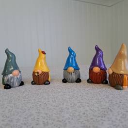 Five small painted gnome figurines lined up on a tabletop