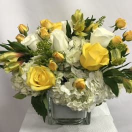 Yellow and white rose bouquet in a clear square vase