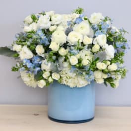 White roses and blue flowers in a light blue vase