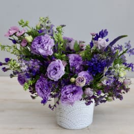 Purple floral arrangement in a white lace-patterned vase