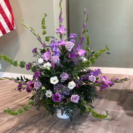 Large purple and white floral arrangement in a white vase
