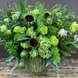 Green floral arrangement in a ribbed vase with sunflowers and hydrangeas
