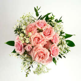 Round bouquet of pink roses and white accent flowers against a white background