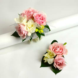 Pink and cream rose corsages with ribbon and leaves