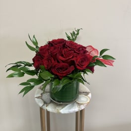Red roses arranged in a green vase with glossy foliage