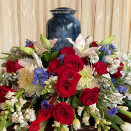 Large floral arrangement with red roses, white lilies, and blue flowers in a blue vase