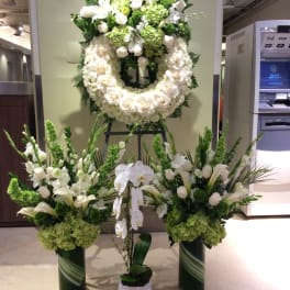 Large white and green funeral floral display with wreaths and standing arrangements