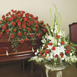 Casket spray of red roses and white lilies beside a matching standing arrangement