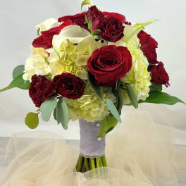 Bouquet of red roses, white calla lilies, and pale hydrangeas