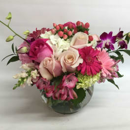 Pink and white mixed flower arrangement in a round glass vase