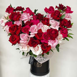 Heart-shaped bouquet of red and pink roses in a black box