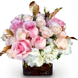 Pink and white roses arranged in a square glass vase