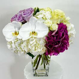 Bouquet of white orchids, hydrangeas, and roses in a clear glass vase