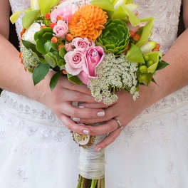 Bride holding a colorful bouquet with pink roses and orange blooms