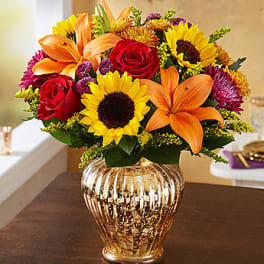 Bouquet of sunflowers, red roses, and orange lilies in a gold vase