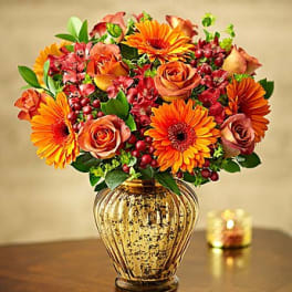 Orange and peach flower arrangement in a glass vase