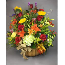 Mixed bouquet in a basket with red roses, lilies, and yellow blooms