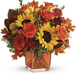 Autumn bouquet of roses and sunflowers in a square glass vase