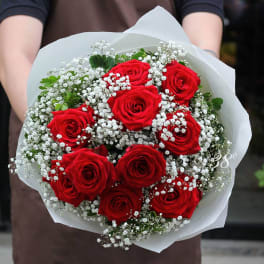 Bouquet of red roses with white baby's breath in white paper wrap