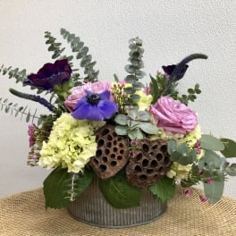 Mixed bouquet in a metal container with pink, purple, and yellow blooms