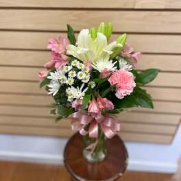 Pink and white mixed bouquet in a glass vase with a pink ribbon