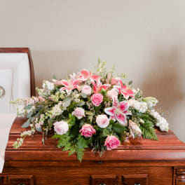 Pink lilies and roses arranged on a wooden casket