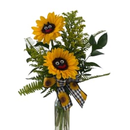 Tall sunflower arrangement with smiling faces in a clear glass bottle with a checked sunflower bow.