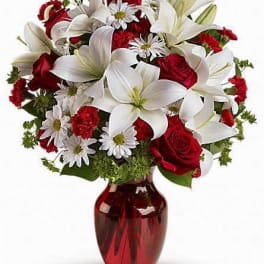 Bouquet of red roses and white lilies in a red glass vase