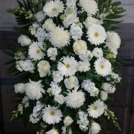 White funeral spray with roses and daisies on a stand