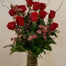 Red roses and pink filler flowers in a clear glass vase